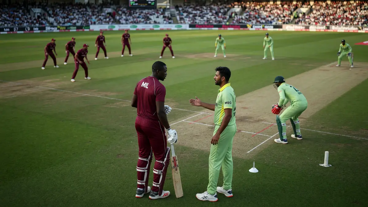 Medium tactical view of a cricket field during a franchise match, with fielders set in position and the bowler approaching the crease