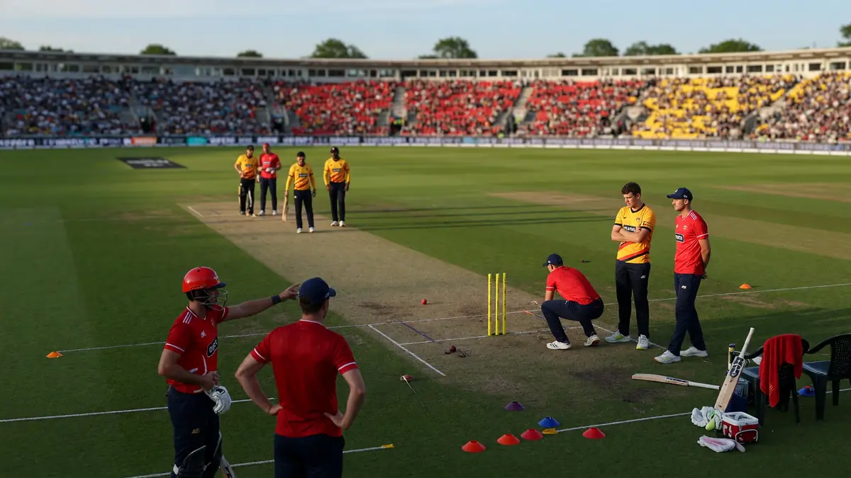 Medium tactical view of a cricket field during a franchise match, with fielders set in position and the bowler approaching the crease